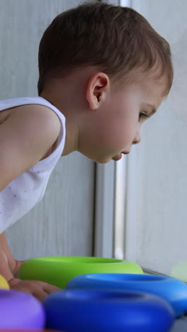 toddler looking out a window with colorful rings