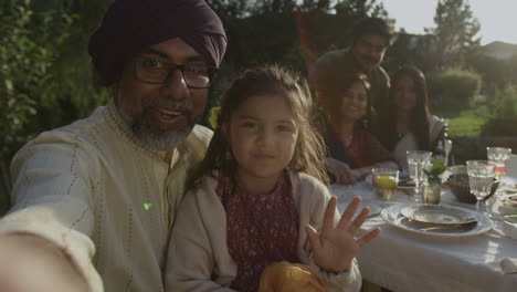 happy multi-generational south asian family taking a selfie at an outdoor gathering