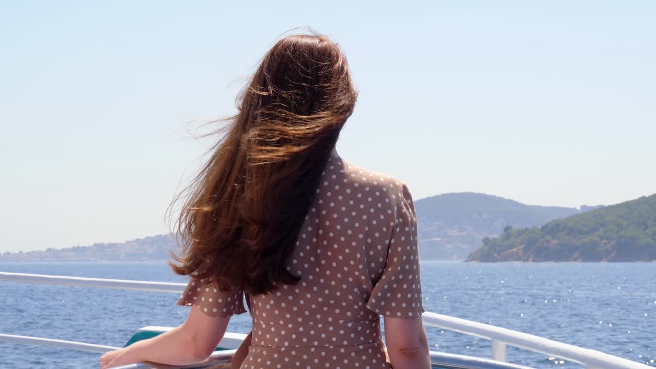 Woman stands at open deck of ferry ship, looking ahead to Princes' Islands