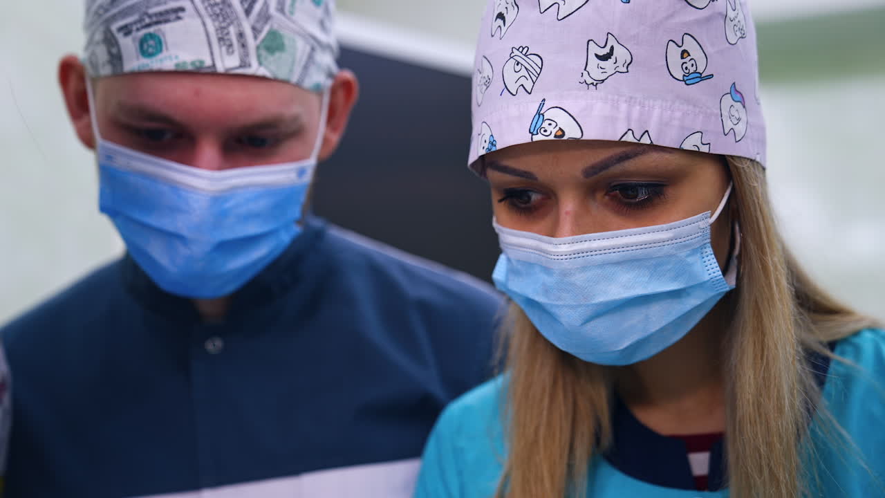 Concentrated look of the students in caps and masks. Students lean closer to see the details. Close up.