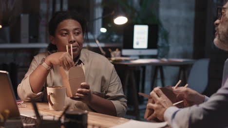colleagues eating late night takeout at office desk