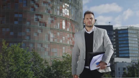 businessman walking on street. confident executive holding documents outdoors