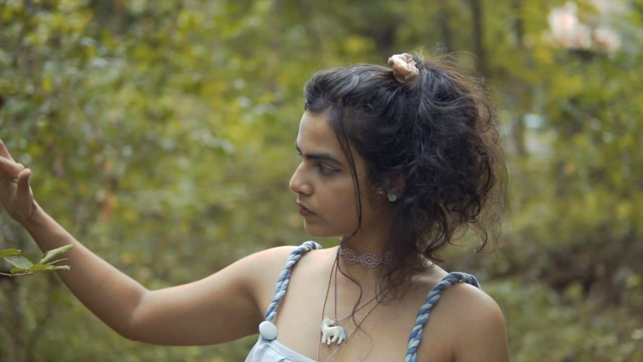 una mujer de cabello oscuro mirando las hojas en un bosque