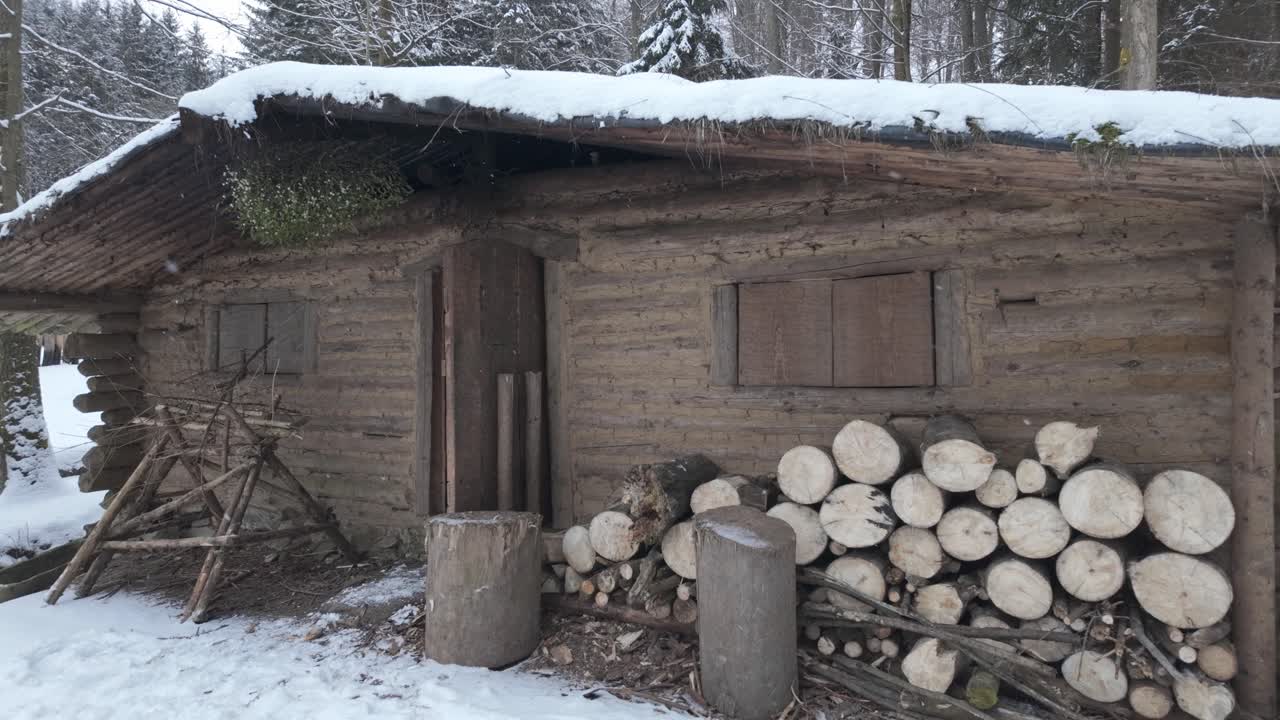 Primitive wooden house in winter. Snow-covered Slavic prehistoric village survives the cold in nature
