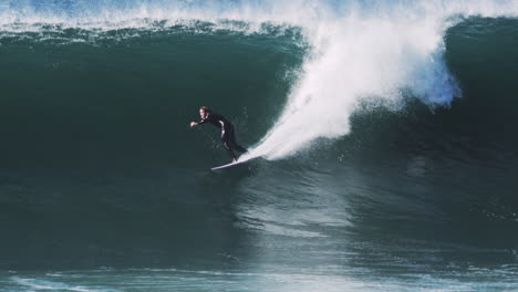 surfer's silhouette inside glowing green tube illuminated by bright offshore light
