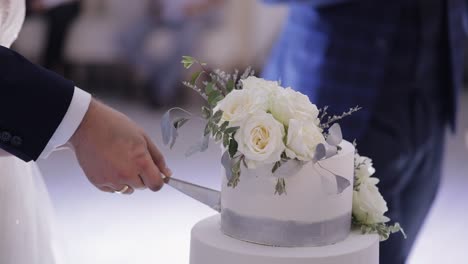 Newlyweds-cut-the-wedding-cake,-lovely-bride-and-groom-couple-cutting-dessert-with-a-knife,-indoors