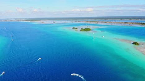 Paraíso-Laguna-De-Los-7-Colores-Con-Barcos-Navegando-Por-Las-Aguas-Turquesas,-Una-Toma-Panorámica-Aérea-Con-Drones