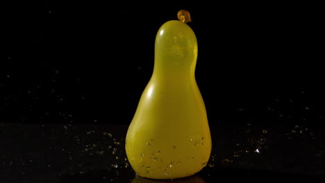 yellow water balloon falling on black background