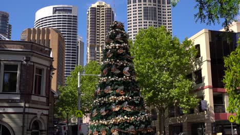 sydney, new south wales, australia - christmas tree with beautiful christmas decorations and high rise buildings in the background on a sunny weather - slow motion closeup shot