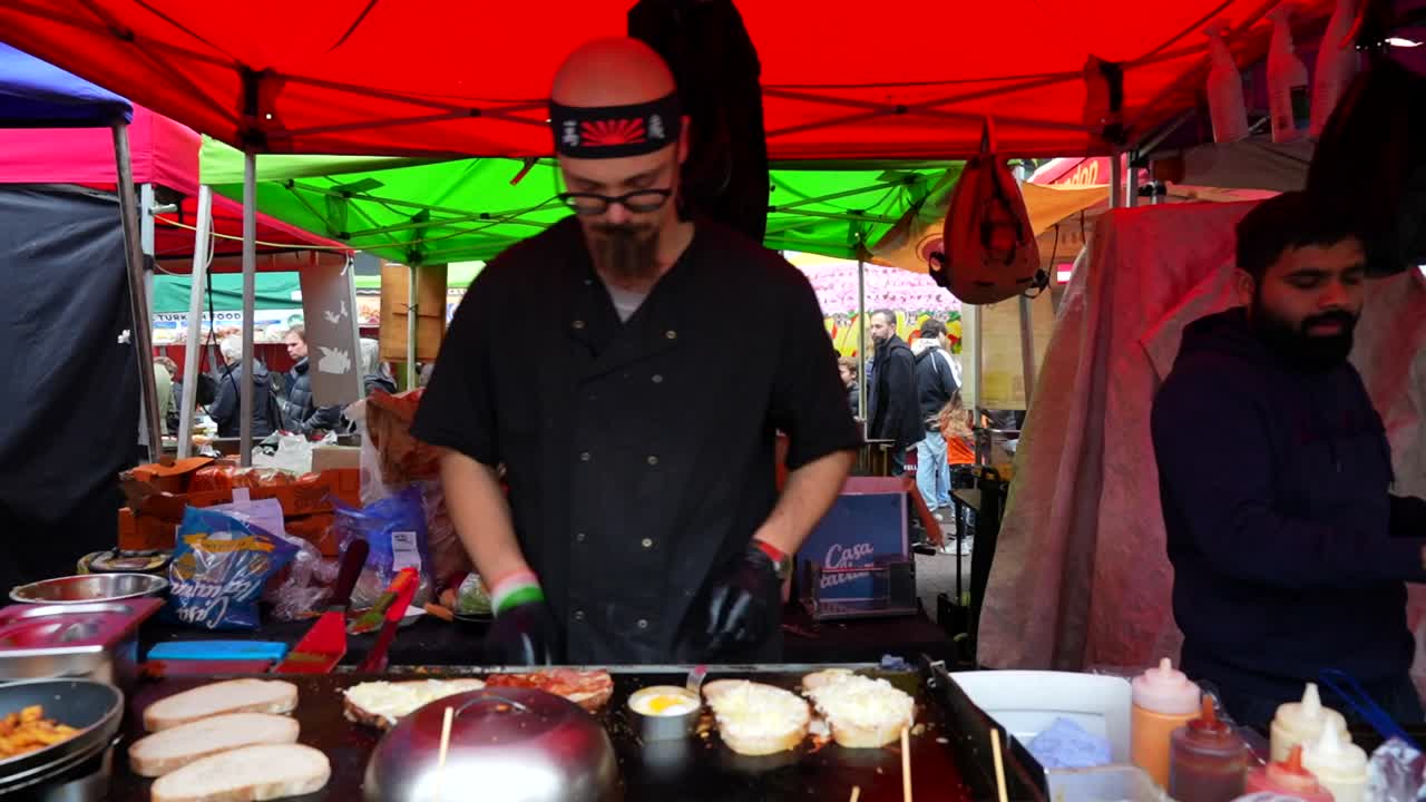 Street food vendor preparing grilled sandwiches at a bustling market on Portobello Road
