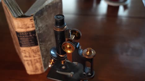 An-old-copy-of-an-anatomy-book-open-next-to-a-vintage-microscope