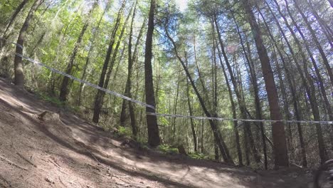 Zeitlupe,-Zwei-Mountainbiker,-Die-Mit-Hoher-Geschwindigkeit-Auf-Der-Forststraße-Vom-Sprung-Bergab-Fahren