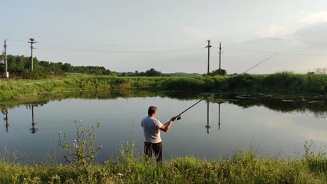 Vista-Trasera-De-Un-Pescador-Que-Usa-Caña-De-Pescar-En-La-Pesca-Con-Caña-En-La-Orilla-Del-Río-En-Rumania-En-Un-Día-Soleado