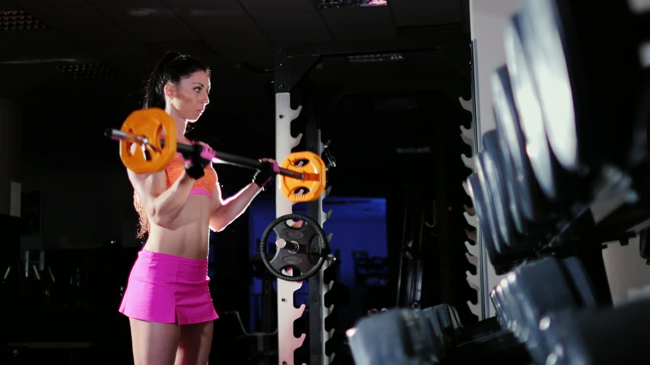 체육관 여성 보디빌딩 슬로우 모션에서 바벨로 훈련하는 강한 운동 여성