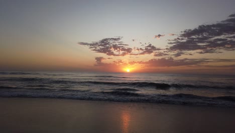panorama del amanecer paisaje de la playa olas que fluyen en la arena dorada reflejo del sol