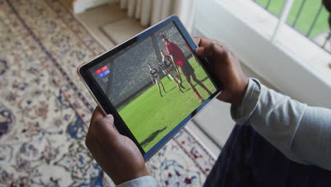 Composite-of-man-sitting-at-home,-watching-rugby-match-on-tablet