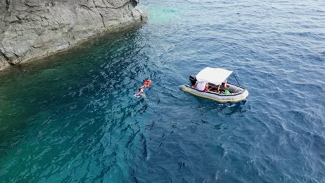 aerial view of male swimmer given a lifejacket by a patrol using a zodiac inflatable boat