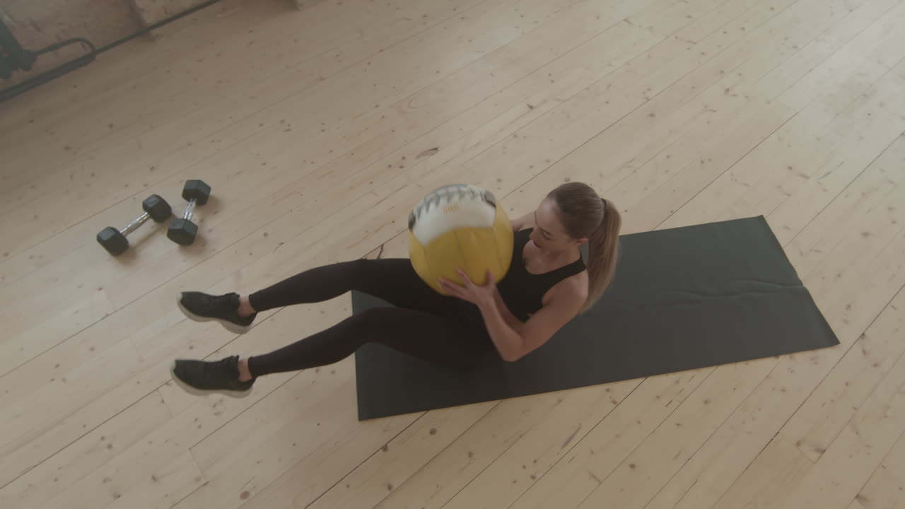 Donna in forma che fa crunch laterali con la palla da fitness