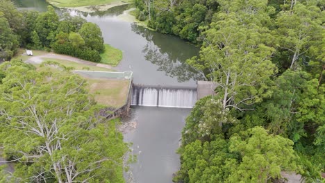 aerial footage of tallebudgera creek dam surrounded by lush greenery, captured in soft daylight with a steady camera
