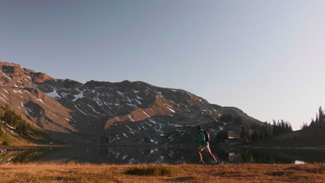 person trail running at sunrise next to lake on mountain, slow motion