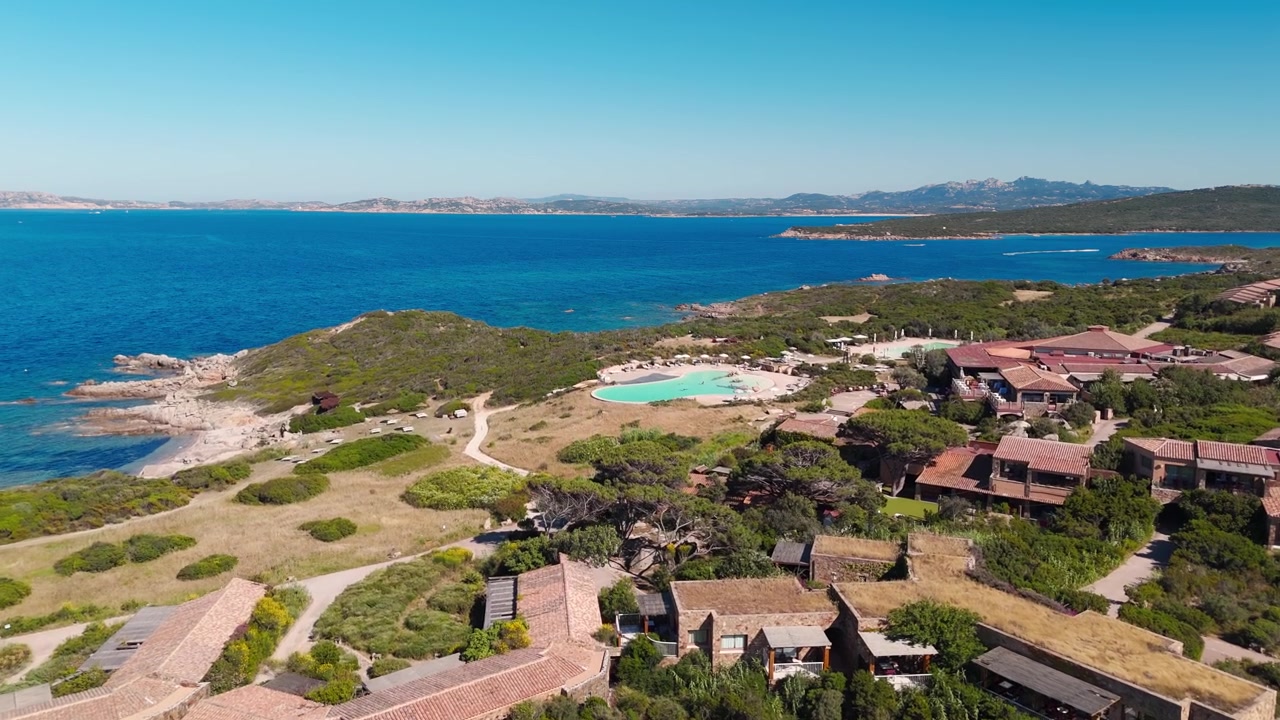 Vista aerea di ville costiere e piscina che si affacciano su un mare azzurro e limpido in una giornata di sole