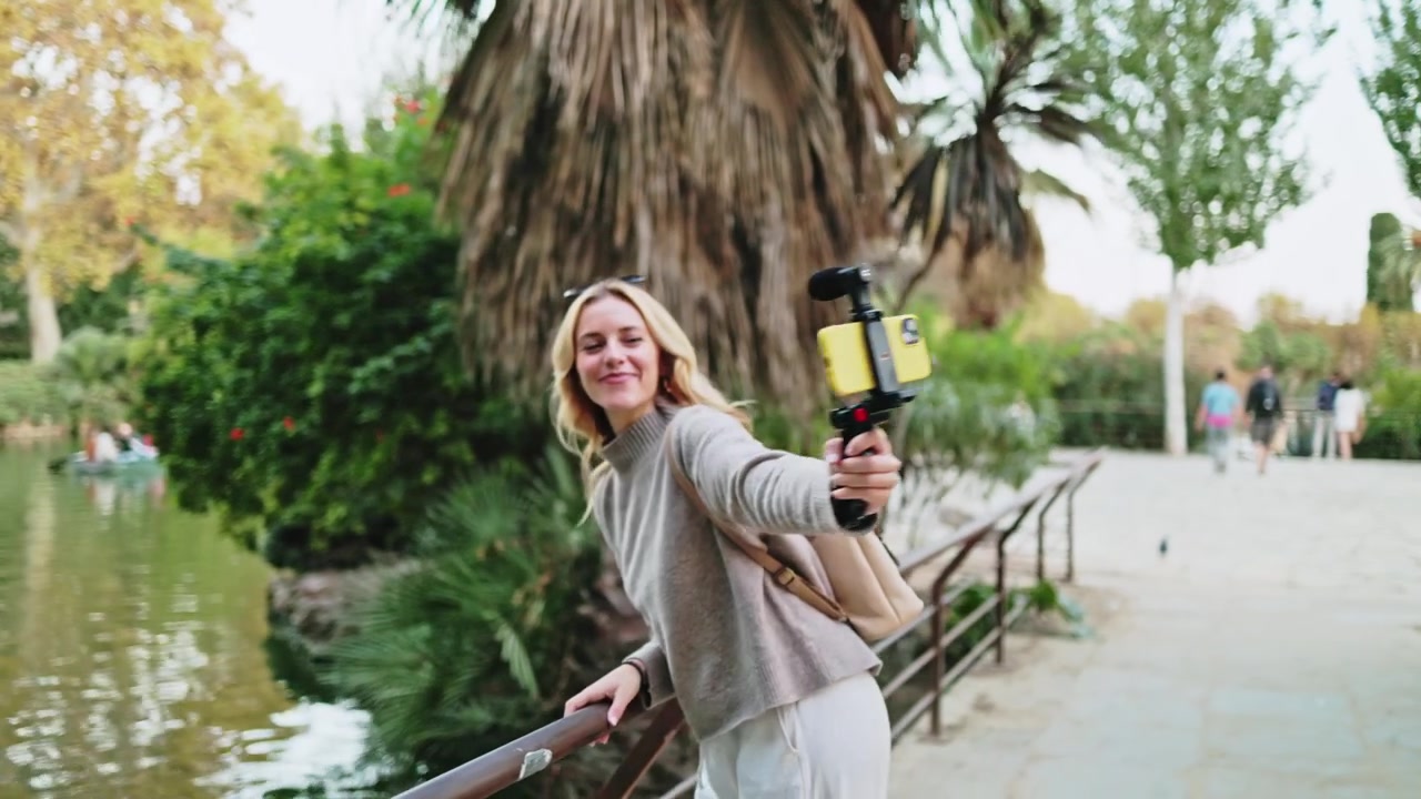 Donna sorridente che fa vlogging con smartphone e gimbal al parco