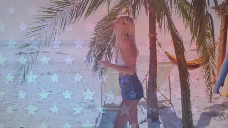 múltiples estrellas parpadeantes contra una mujer caucásica usando un teléfono inteligente y sonriendo en la playa