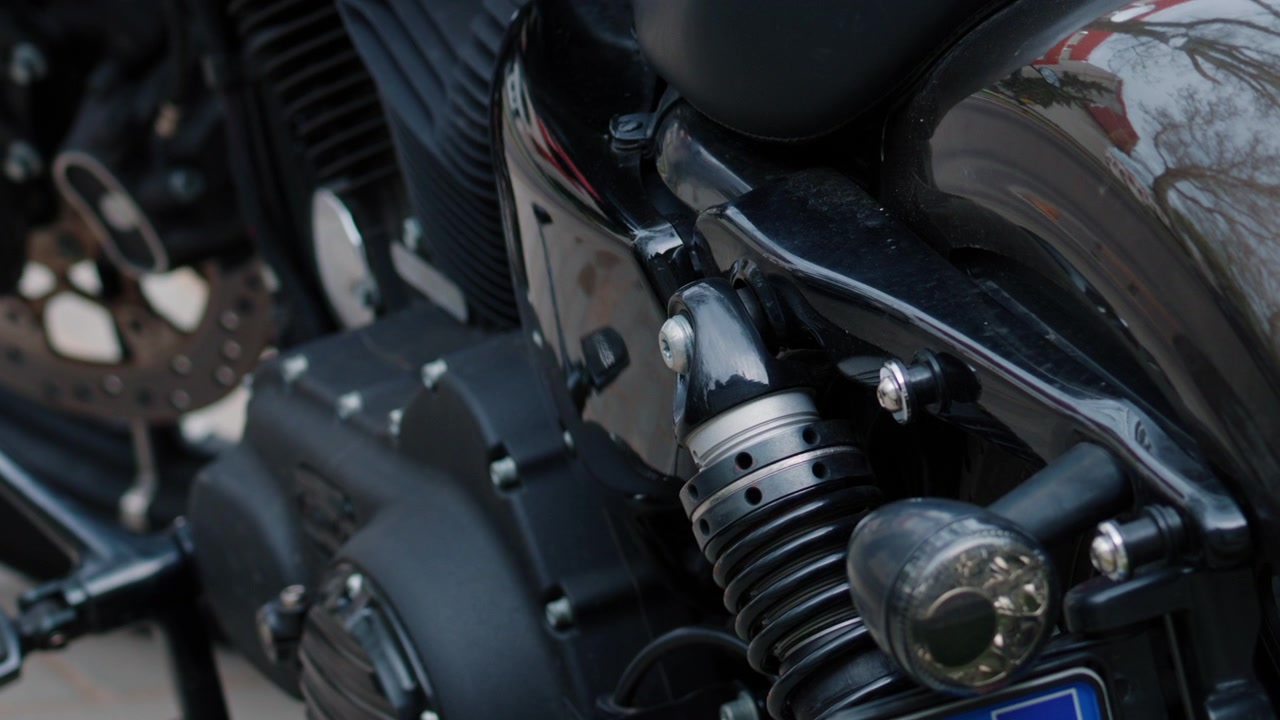 Gros plan sur un moteur de moto noir, la suspension arrière et les détails brillants de la carrosserie.