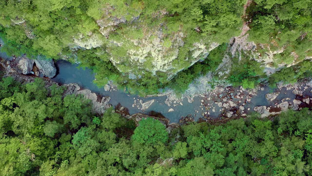 Aerial Top Down View Of River Snaking Through Forested Cliffs. Pedestal Down