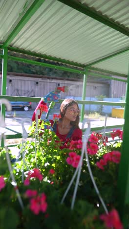 woman watering hanging plants at a garden center