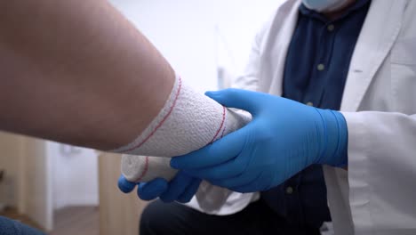 médico anónimo vendando el brazo de un paciente en el hospital