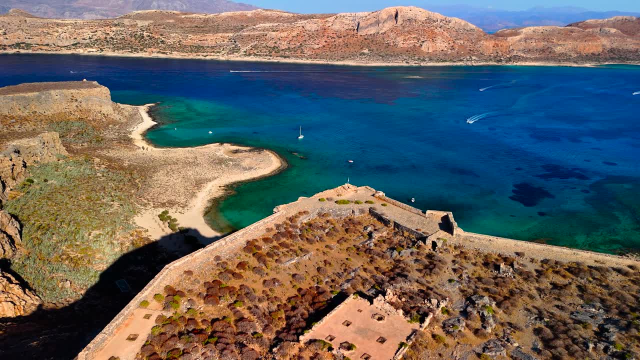 Discover the stunning landscape of Crete featuring ancient ruins beside a beautiful coastline at sunset. Experience the captivating blend of history and nature in this serene location