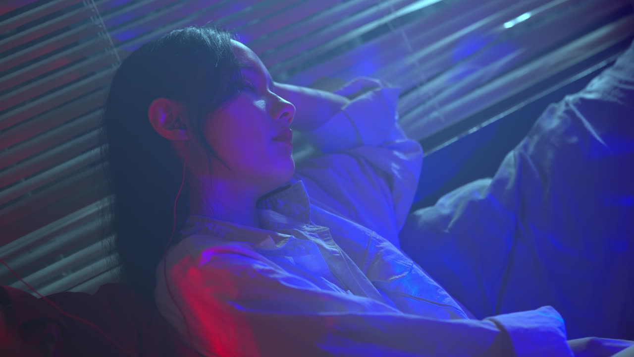 Donna pensierosa sotto una luce neon blu e rossa.