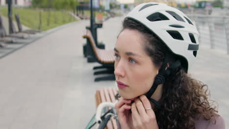 young woman in formal clothes sitting on bench and wearing a bicycle helmet 1