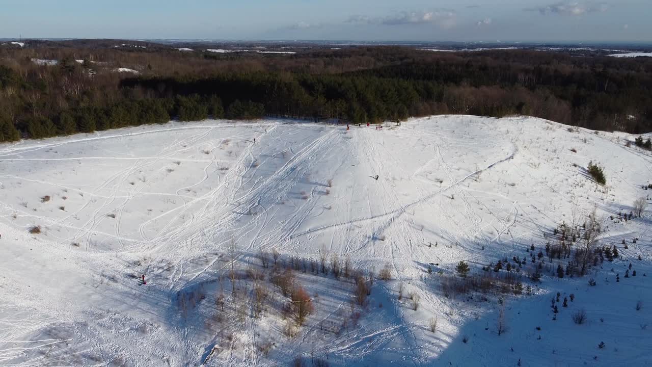 Persone che fanno snowboard e slittano giù per la collina in un parco ricreativo all'aperto.
