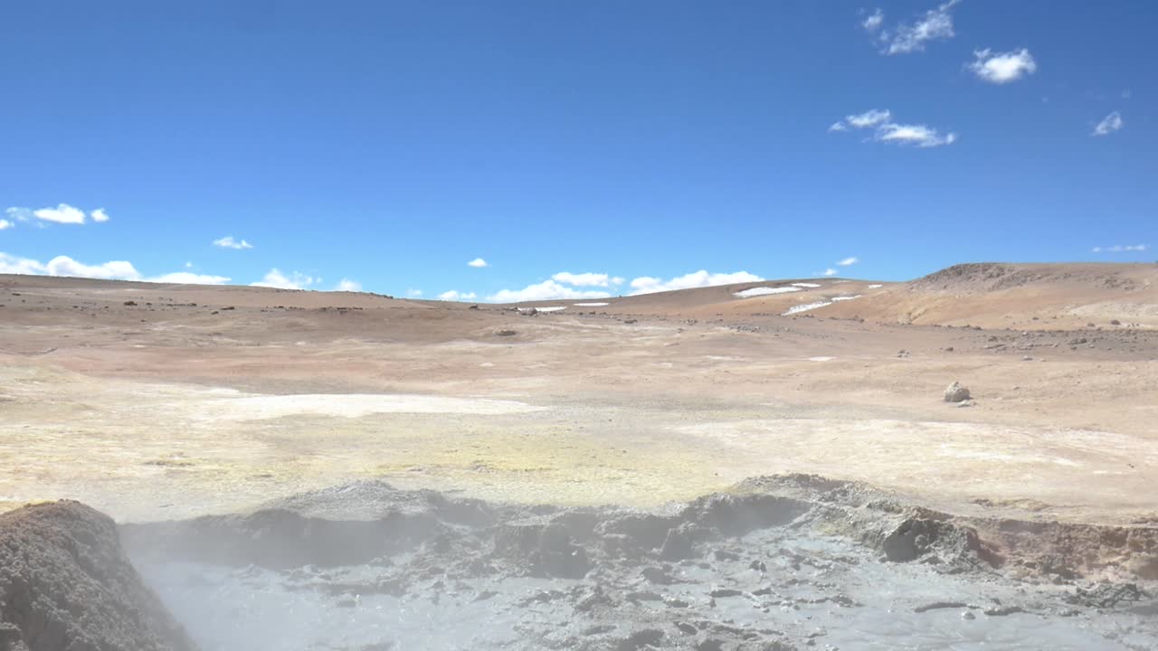 una toma amplia del desierto en la frontera de bolivia y chile, una piscina volcánica fangosa en primer plano