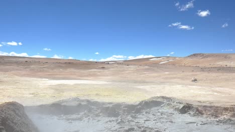 a wide shot of the desert on the border of bolivia and chile, a muddy volcanic pool in the foreground