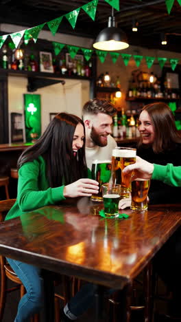 friends celebrating st. patrick's day with green beer at a bar