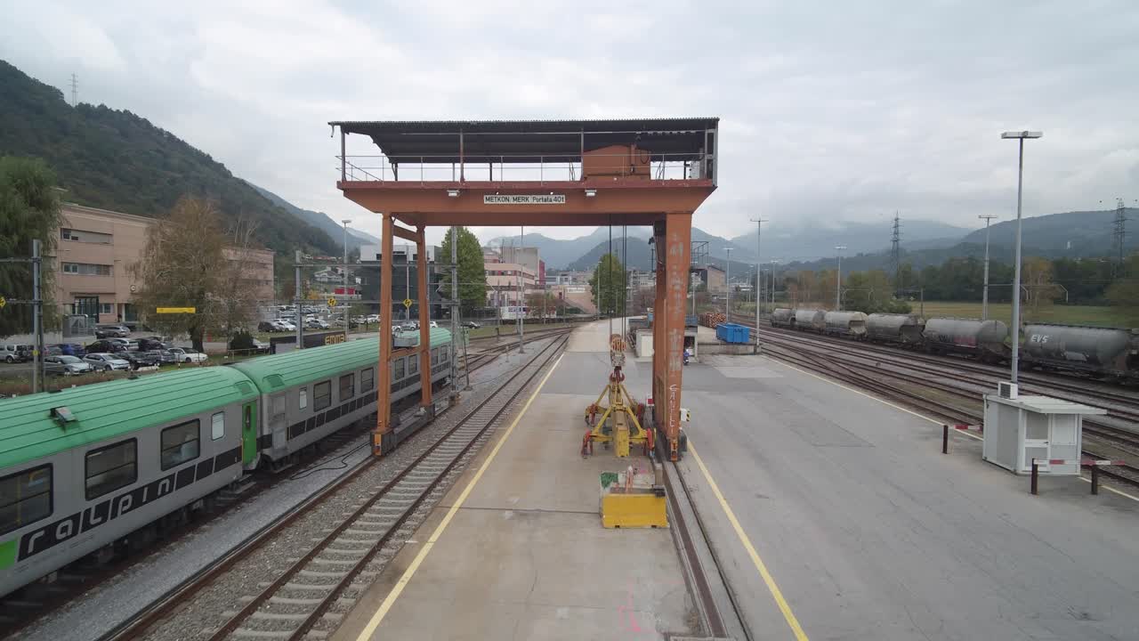 Train station aerial footage. Passing under a cargo metal structure.