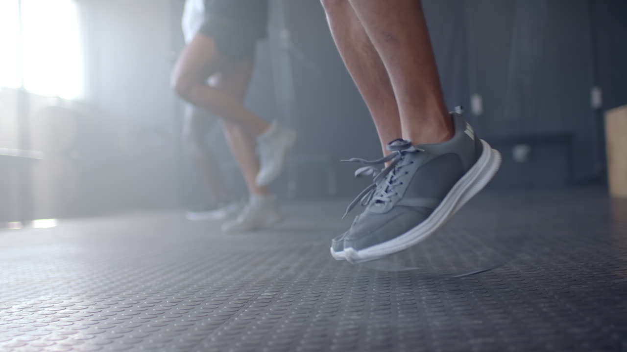 Jumping in gym, men exercising with focus on legs and athletic shoes