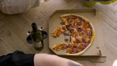 top view of pizza, wine bottle and glasses on a wooden floor