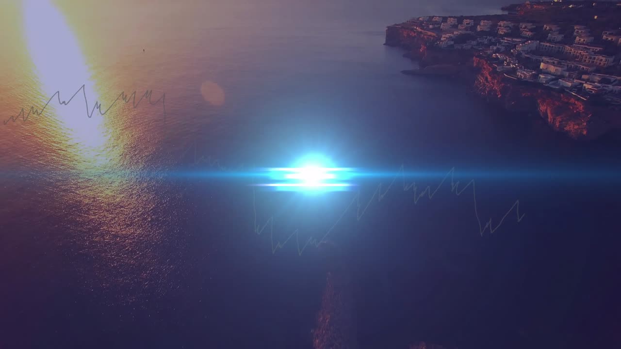 Blue lens flare sweeping, illuminating coastline then revealing sunlit sea and cliffside buildings