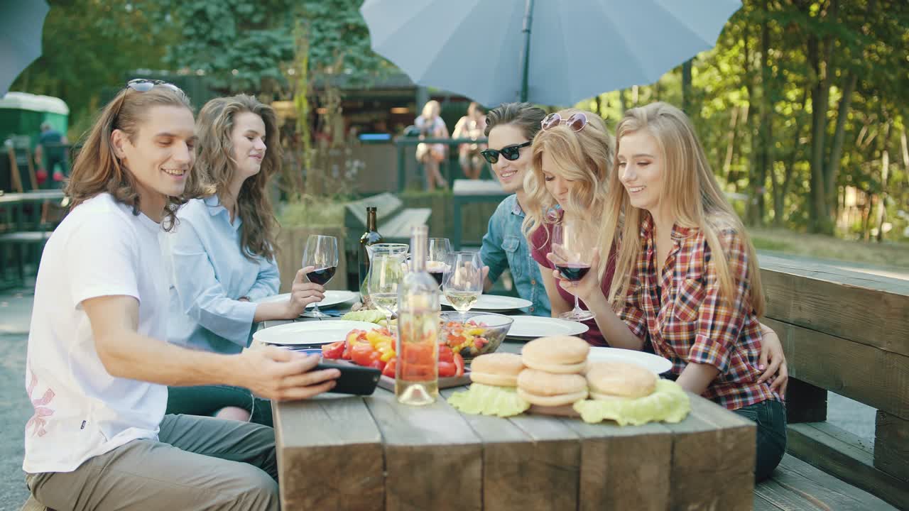 와인을 마시며 드폰으로 사진을 찍는 친구들.