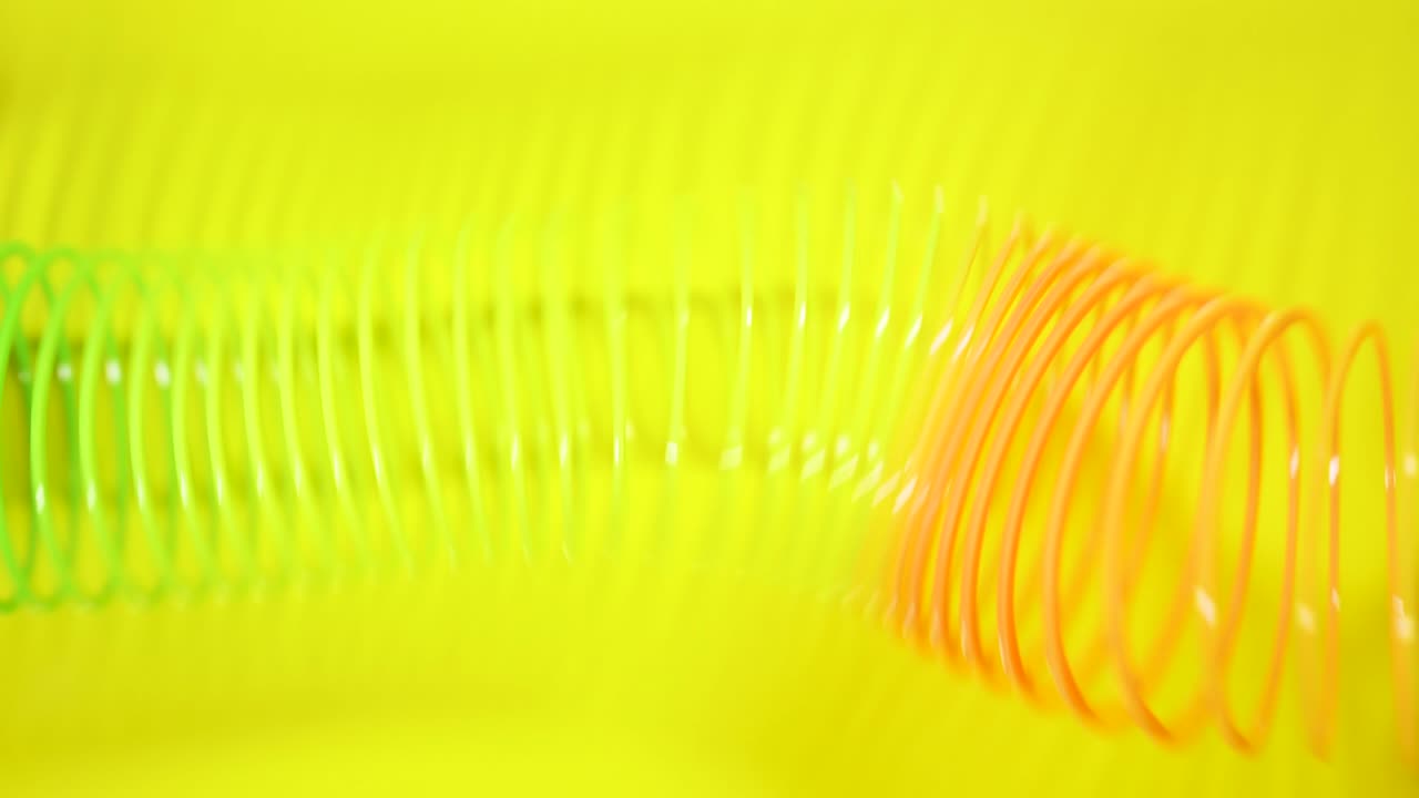 el fondo abstracto retro vintage. el resorte de color arco iris se mueve a través de un fondo amarillo en un patrón de onda. juguete slinky. una onda de movimiento de resorte en espiral de arcoirres un fondo brillante y hermoso.