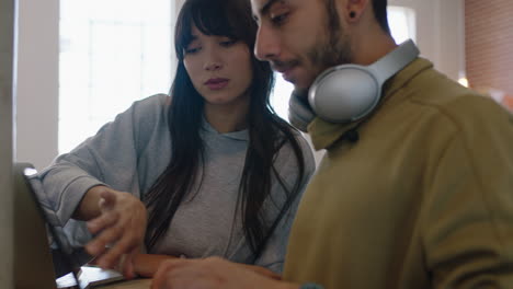 Junge,-Vielfältige-Geschäftsleute-Beim-Brainstorming,-Teamleiterin,-Frau,-Die-Gemeinsam-Ideen-Austauscht-Und-Einem-Kollegen-Zeigt,-Wie-Er-Mit-Einem-Laptop-An-Einem-Trendigen-Arbeitsplatz-Musik-Hört