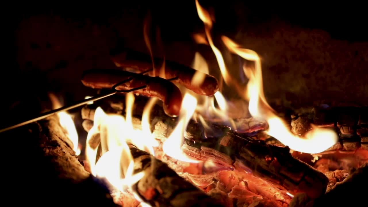 en cámara lenta deliciosas salchichas jugosas, cocinadas en la parrilla con un fuego