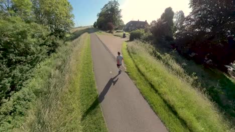 Immersive-follow-swirling-camera-changing-angles-and-perspective-showing-a-male-trail-runner-on-floodplains-valley-dyke