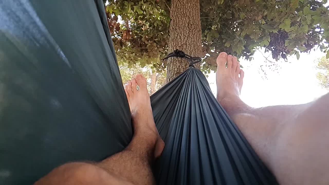 하루를 즐기고 해먹에서 좌우로 스윙하는 행복한 젊은이의 슬로모션