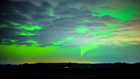 cumulus clouds drift by under the green glow of the northern lights