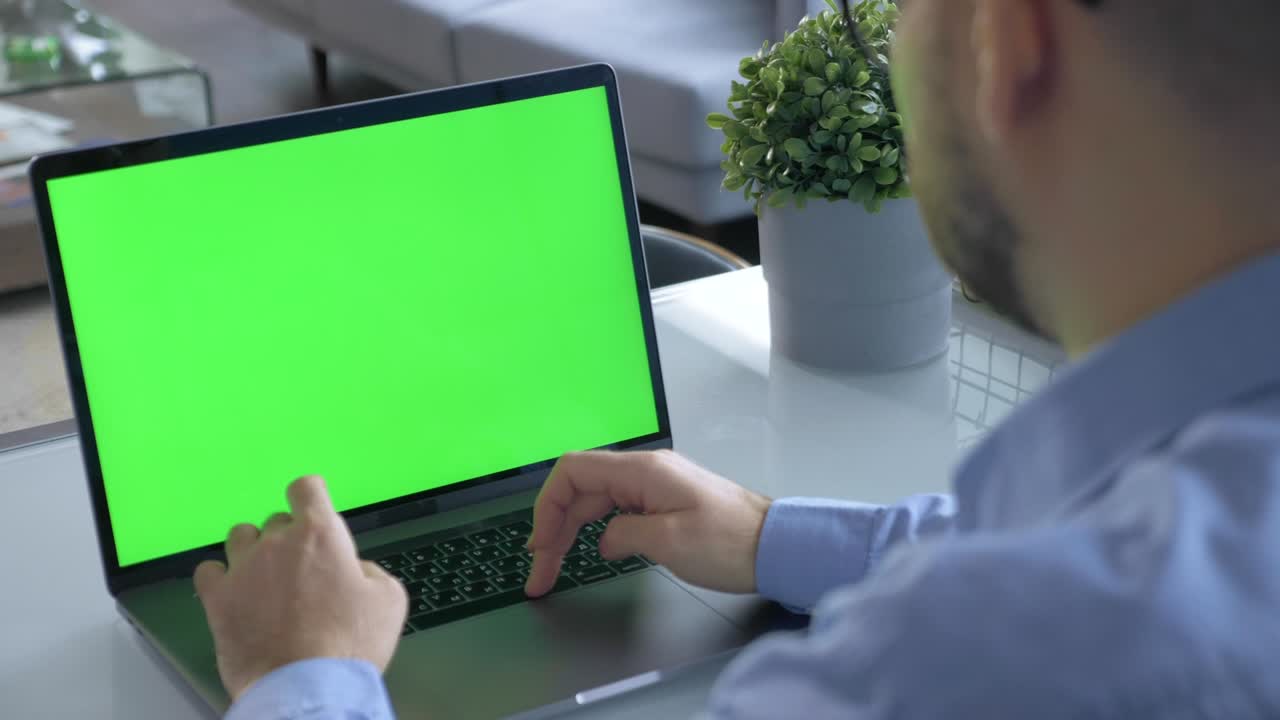 un hombre usando una computadora portátil con una pantalla verde en la oficina en casa